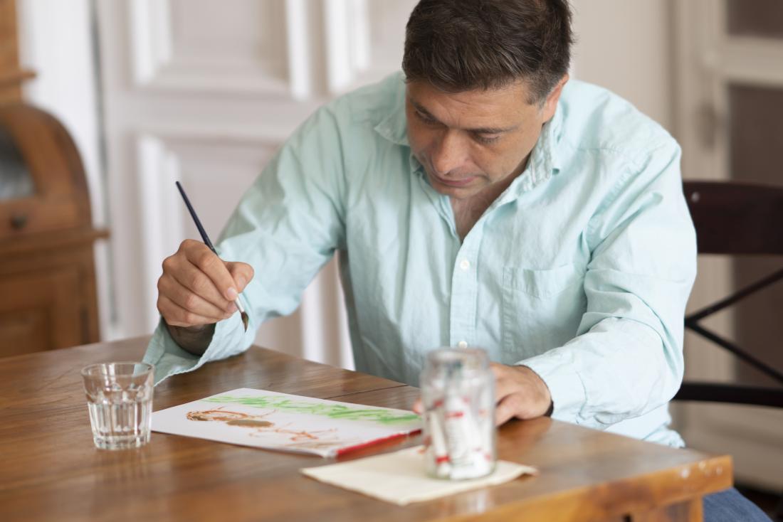 テーブルで絵を描く男性