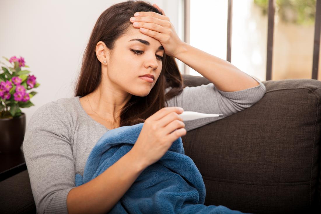 Woman holding a thermometer with a fever