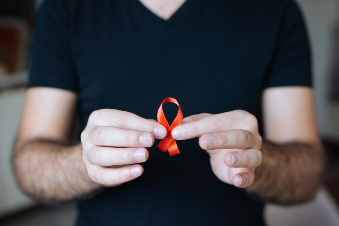 Man holding up red HIV awareness ribbon