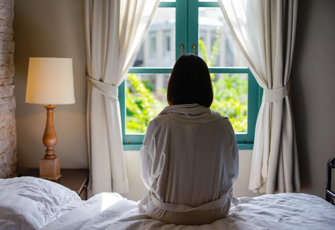woman sitting on the edge of the bed seen from behind