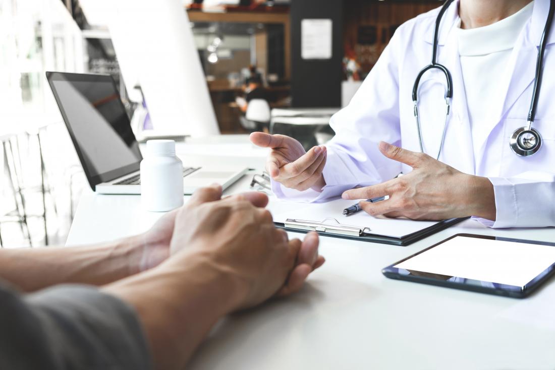 Doctor and patient at desk in office, faces out of view