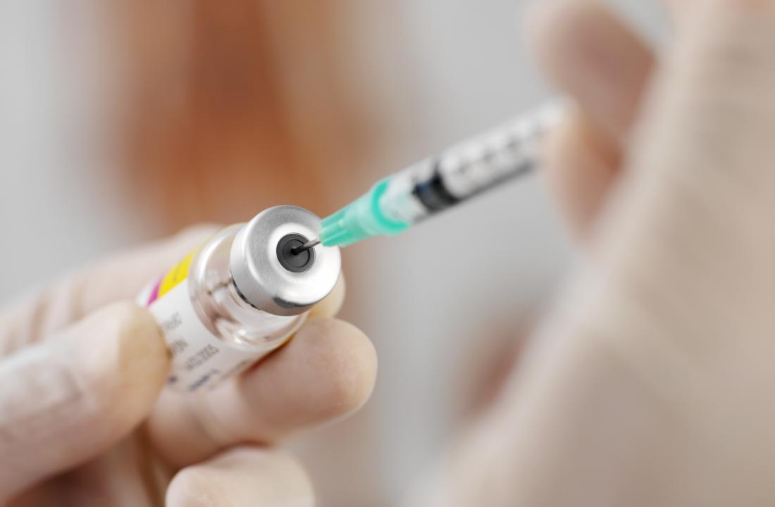 Syringe taking medication from bottle for injection