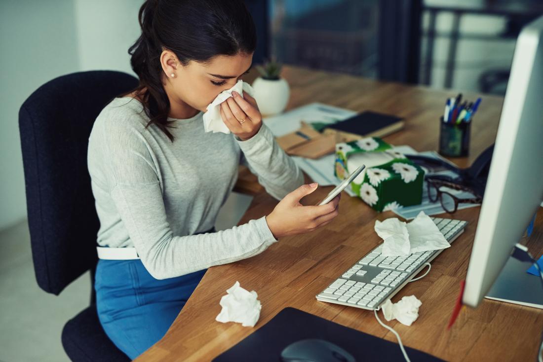 woman blowing nose while at work