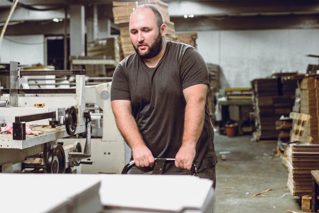 Man working in warehouse or factory pushing and pulling heavy objects
