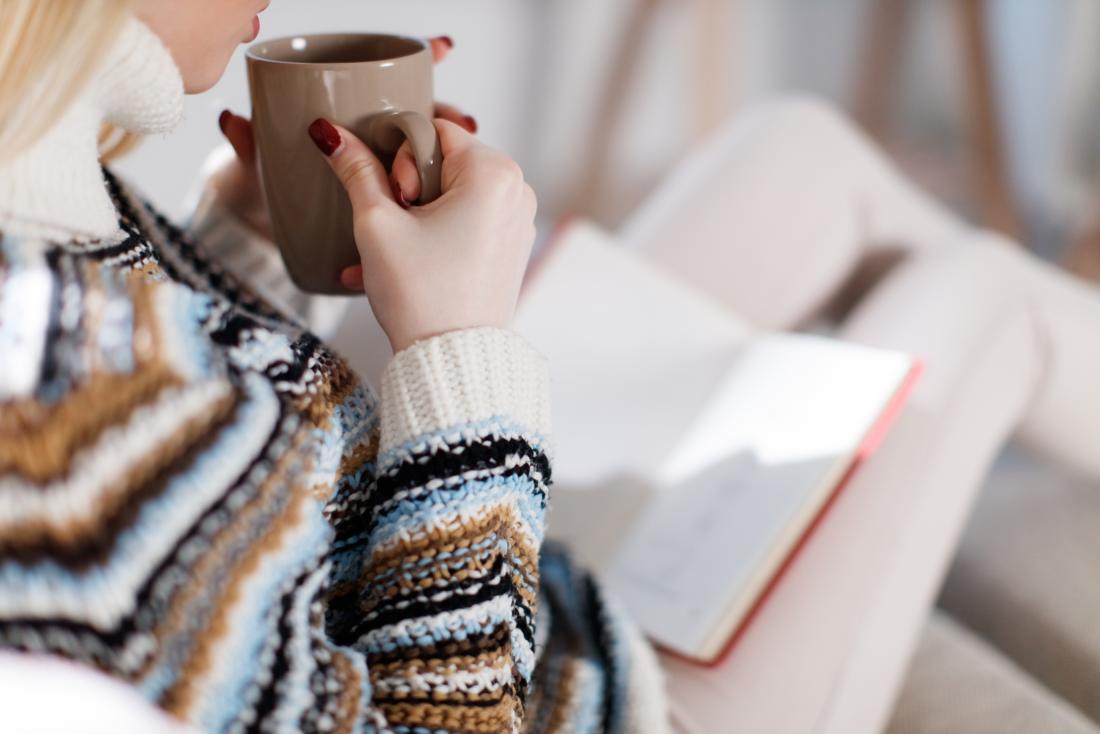 woman reading a book while drinking tea