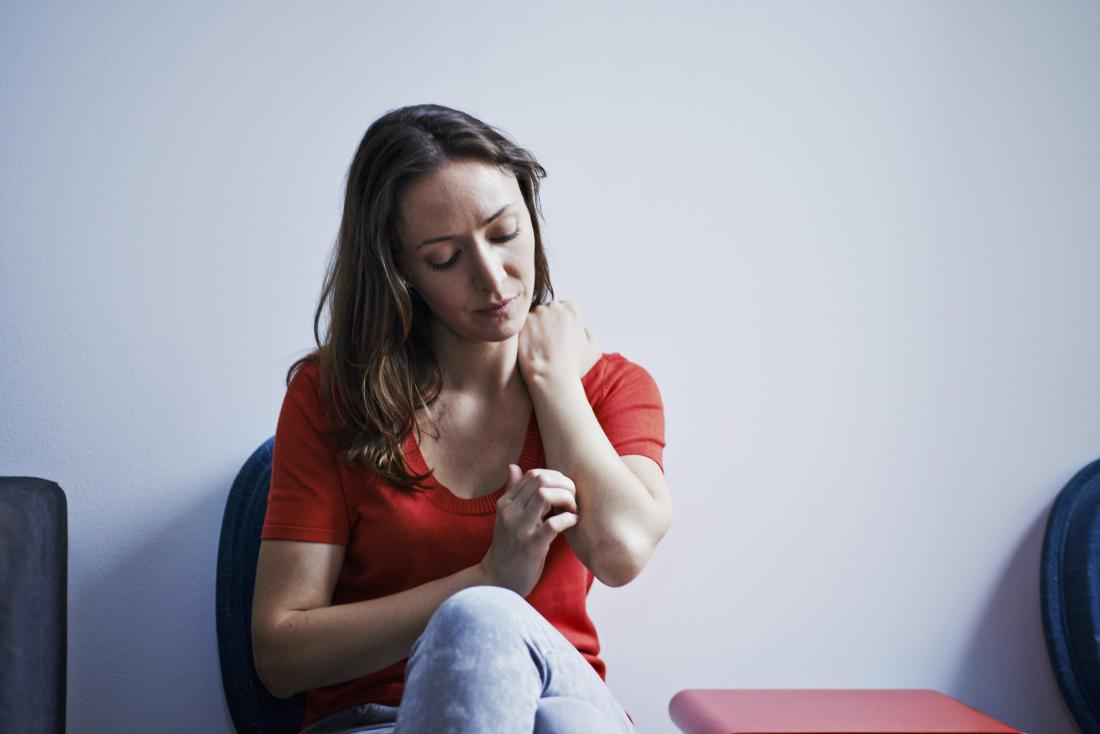 woman sitting in waiting room itching arm