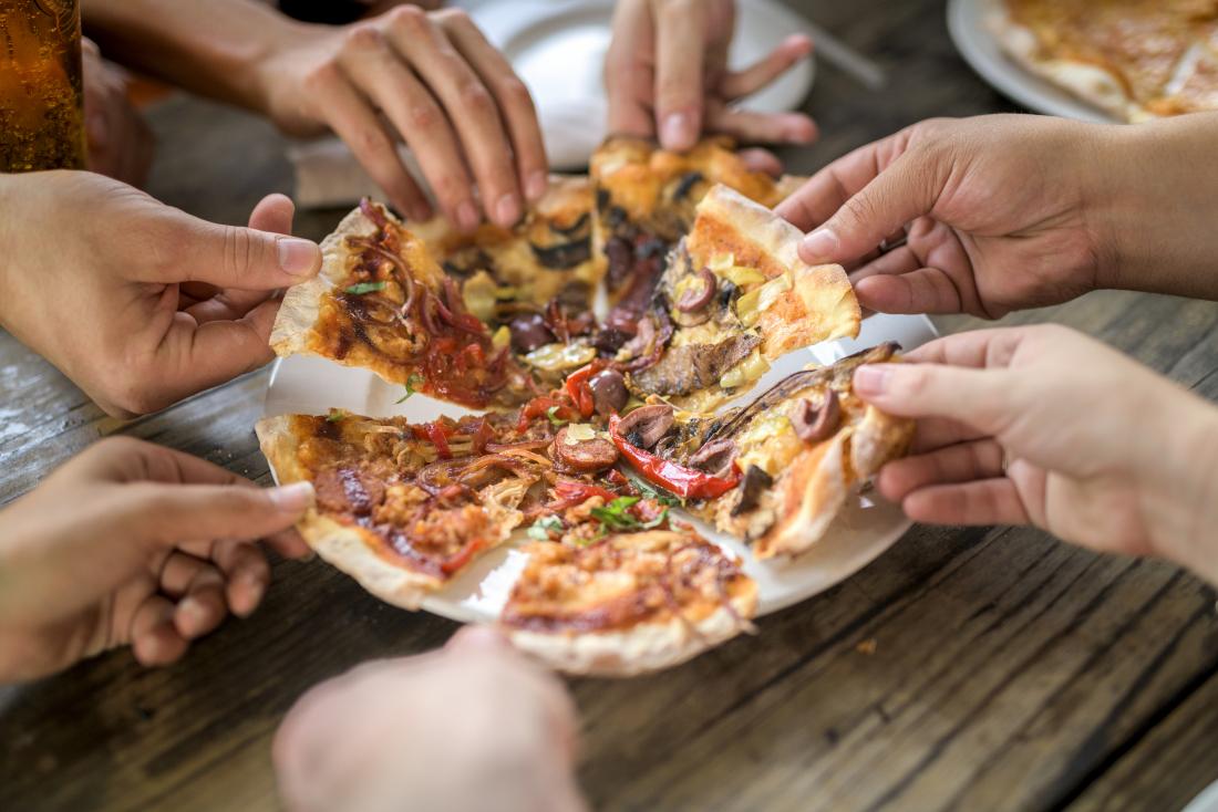 close up of hands dividing pizza