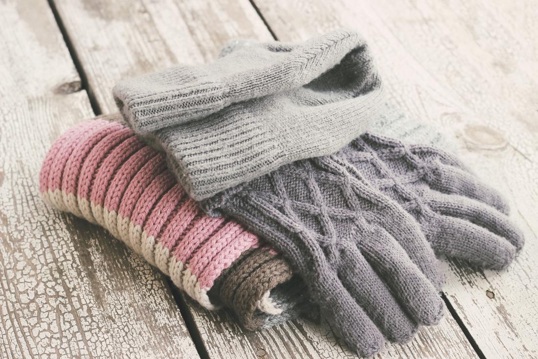 Gloves and scarves piled on wooden table