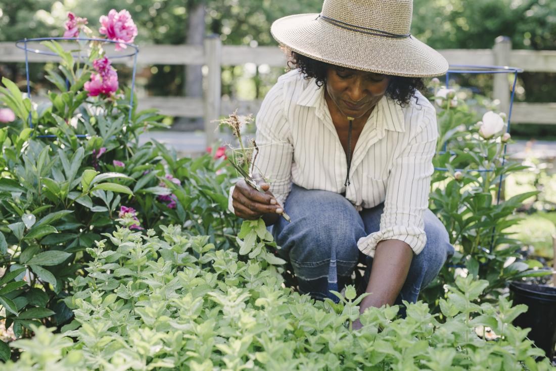 Woman outdoors gardening with sun hat on.