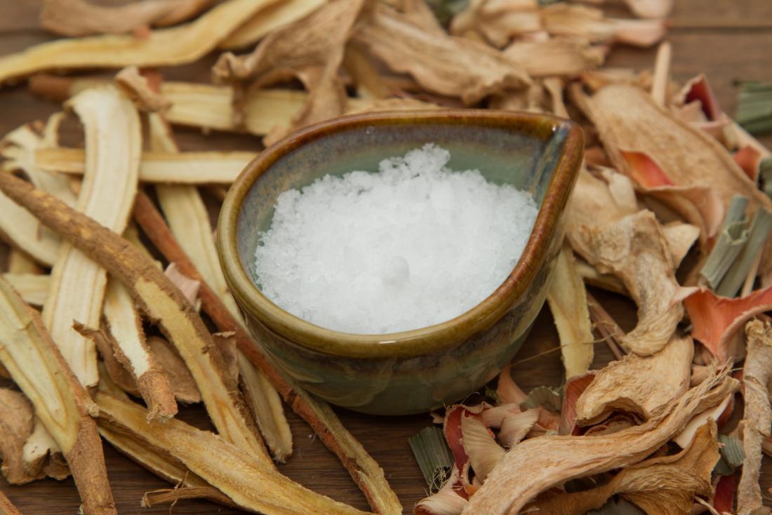 Camphor in a bowl amongst roots and plants on wooden table