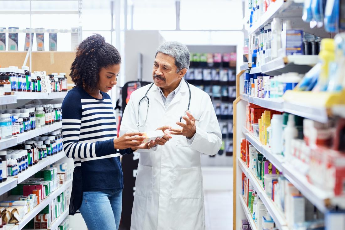 Woman in pharmacy speaking to pharmacist about medication
