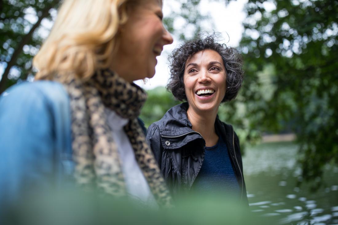 Two mature women friends walking outdoors smiling and laughing