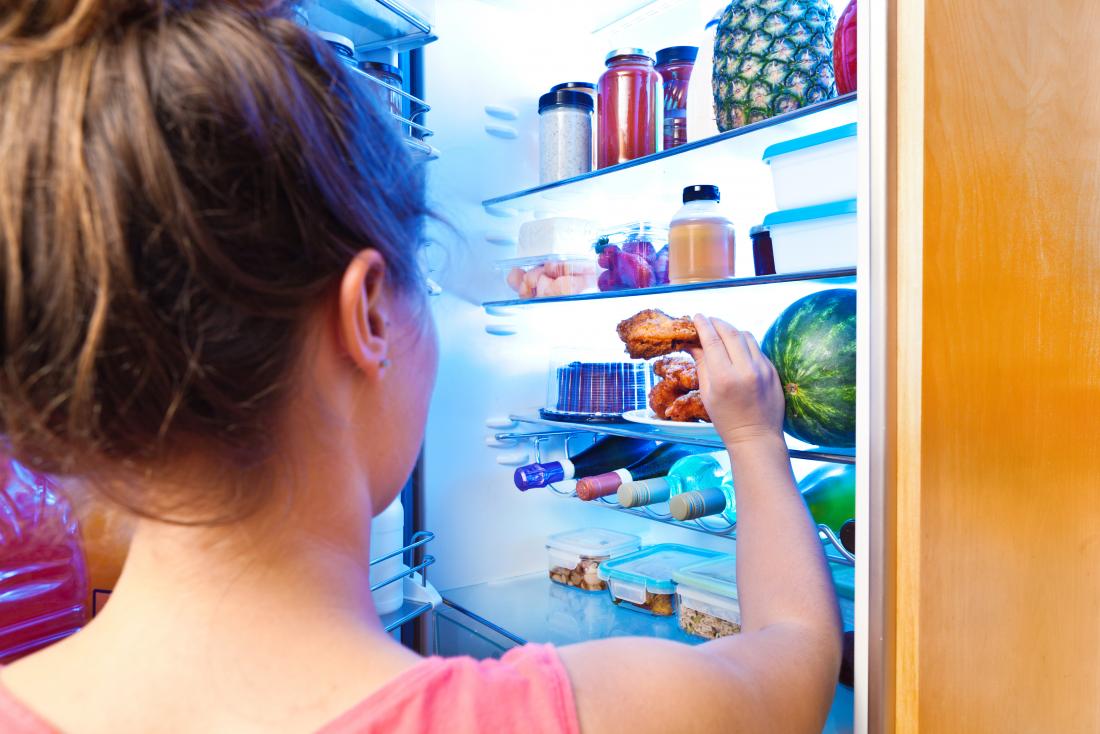 woman taking some cooked chicken out of fridge