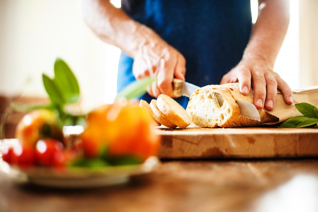 man slicing white loaf of bread