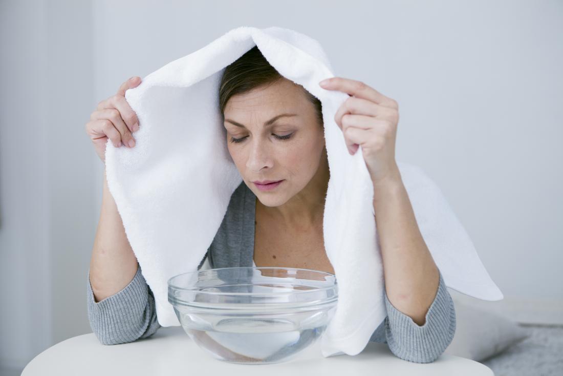 Woman with head over steaming bowl of water to clear sinuses