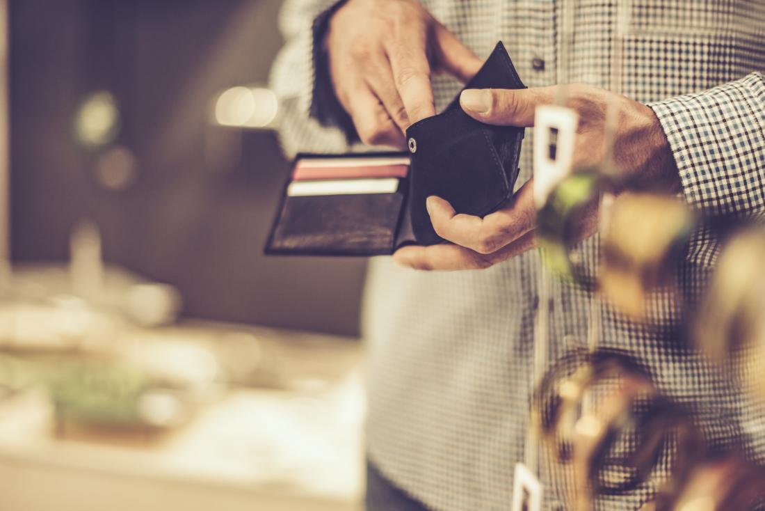 man looking in wallet whilst outside shop