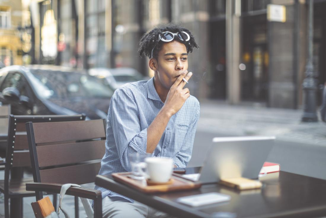 Man smoking cigarette at outdoor cafe in busy street
