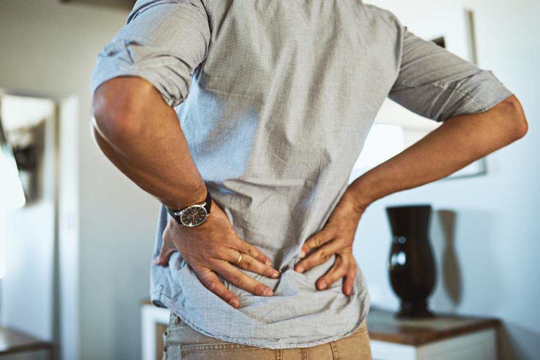 Person holding back in pain while breathing