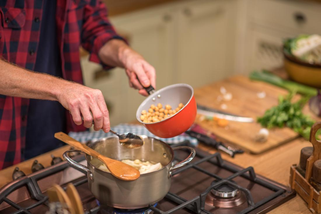 man adding chickpeas to saucepan