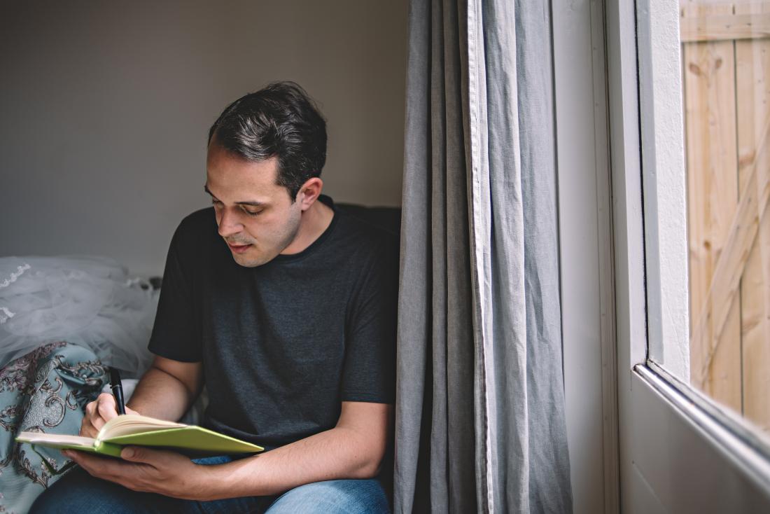 Man writing journal or diary next to window