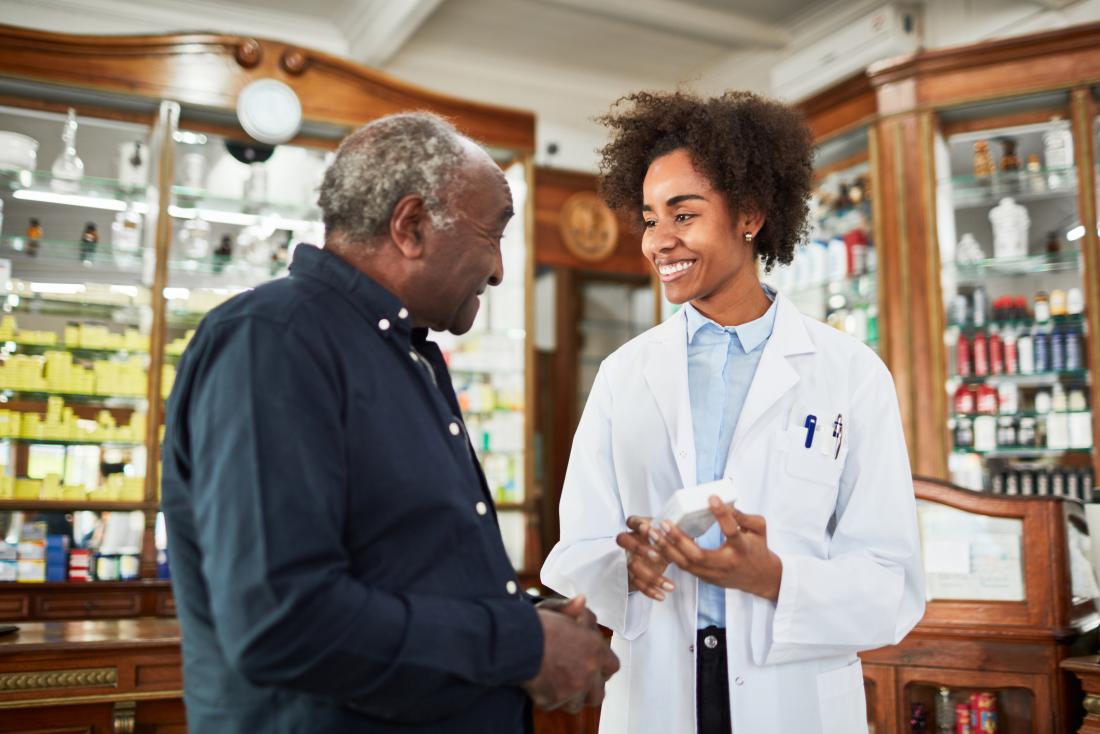 chemist assisting senior man, both smiling