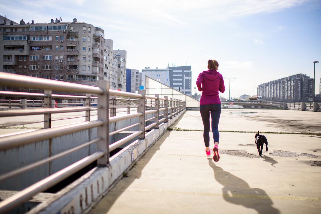 Woman running with her dog which may help get a flat stomach