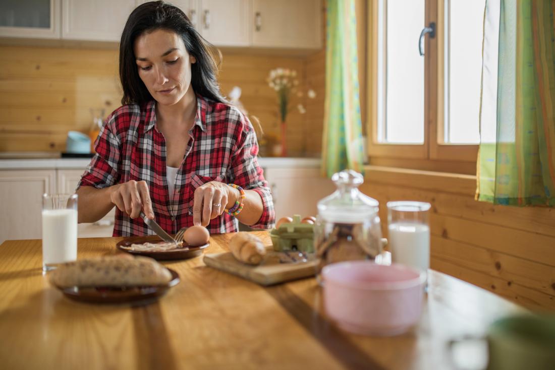 woman sitting at table eating breakfast
