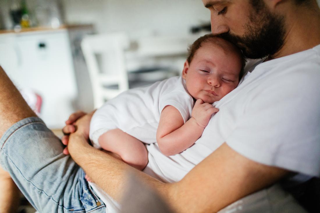 Father sitting while holding sleeping baby