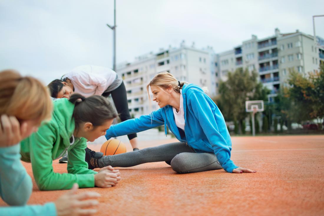 group of young women doing warmup exercises before netball