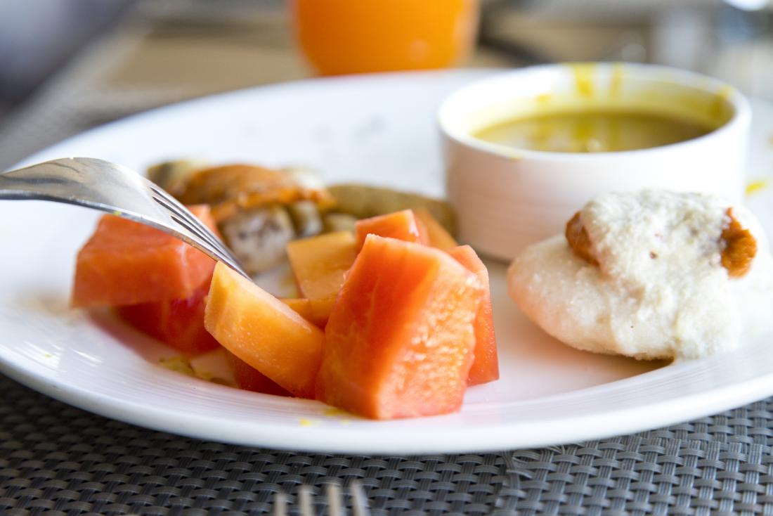 indian diet breakfast option on a plate including idli and fruit