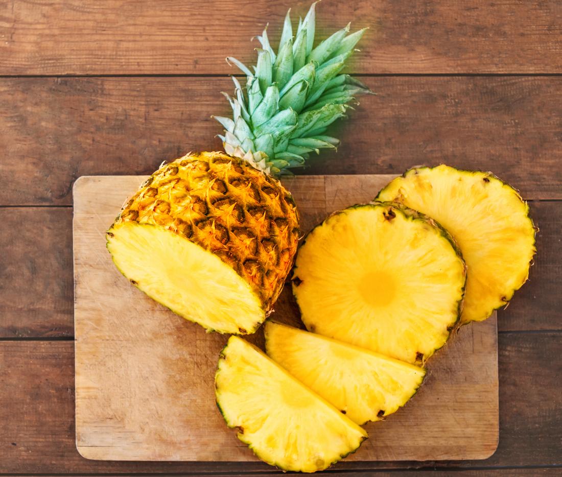 fresh pineapple sliced on chopping board