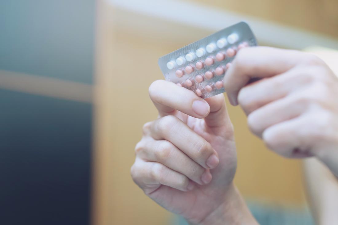 women holding packet of birth control pills to make period come faster