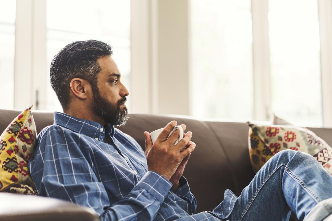 man sitting on settee drinking coffee