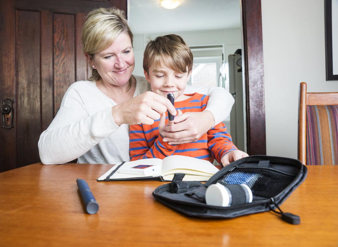 mother helping son check his glucose levels