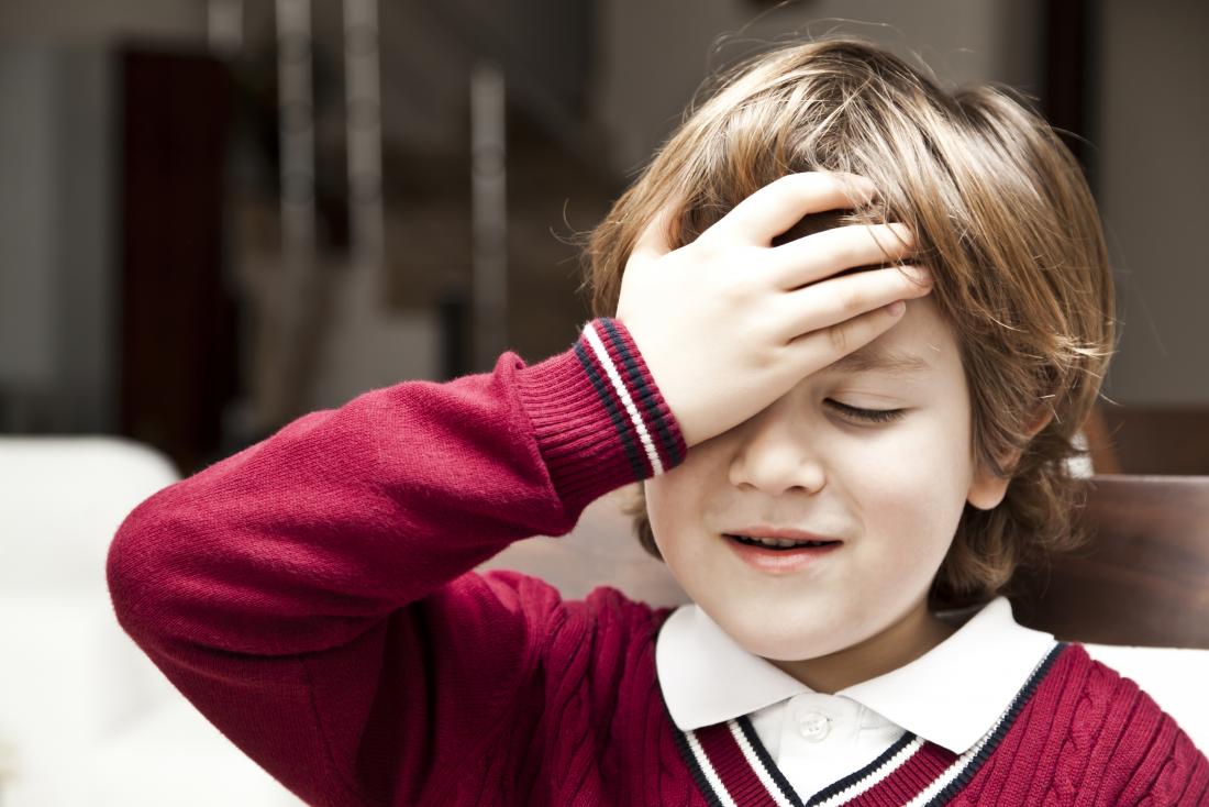 young boy holding his head