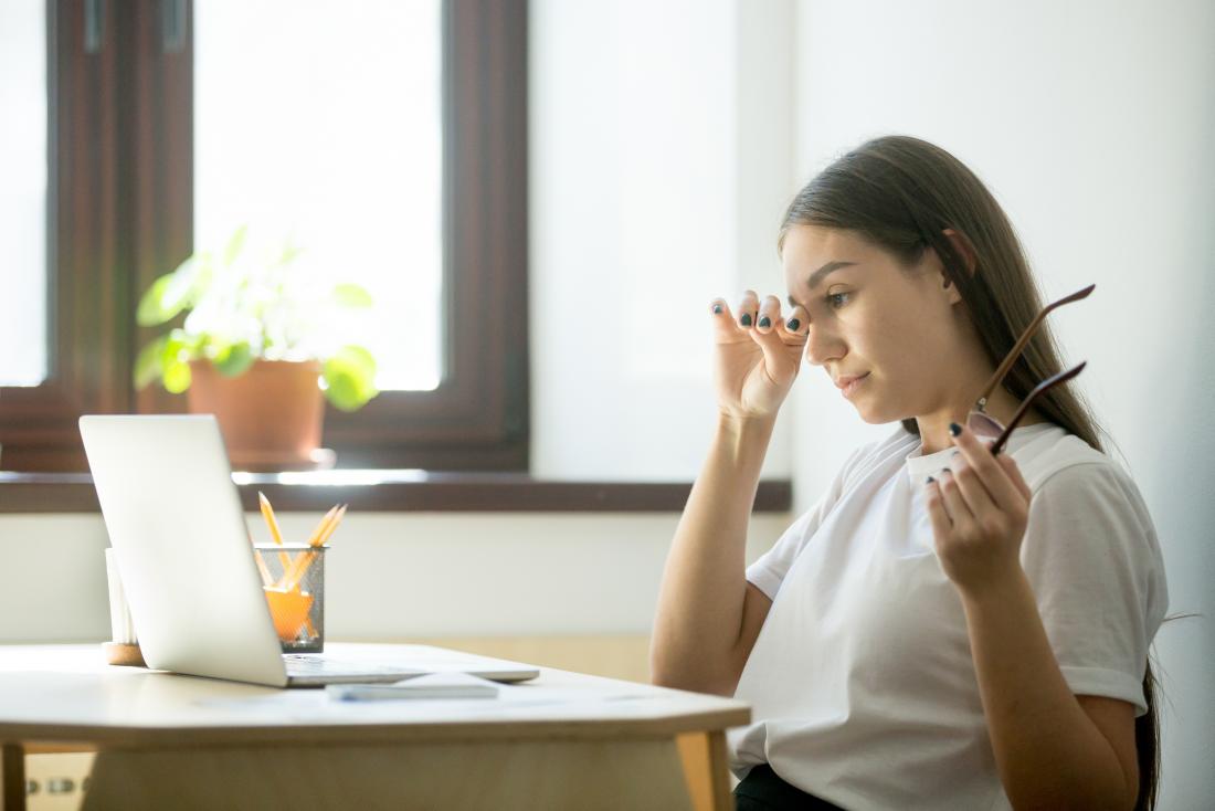 woman with a headache and fatigue at her desk