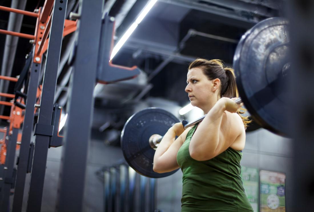 woman lifting weights and bodybuilding in gym