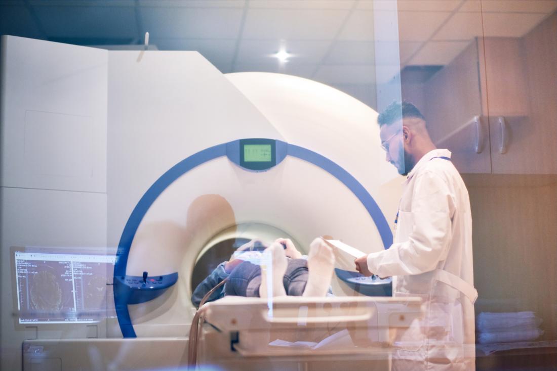 Patient with multiple sclerosis in a powerful mri scanner with researcher monitoring.