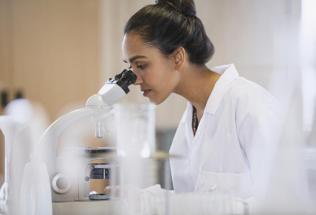 researcher looking through microscope