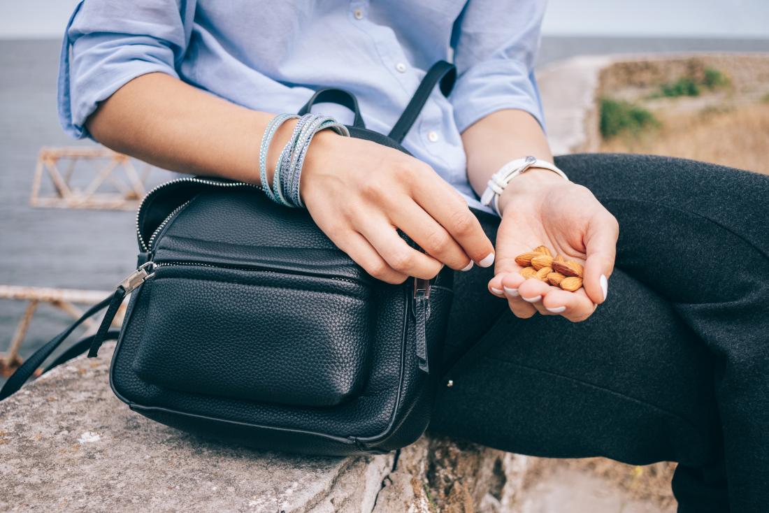 A person outside having almond nuts as a snack.
