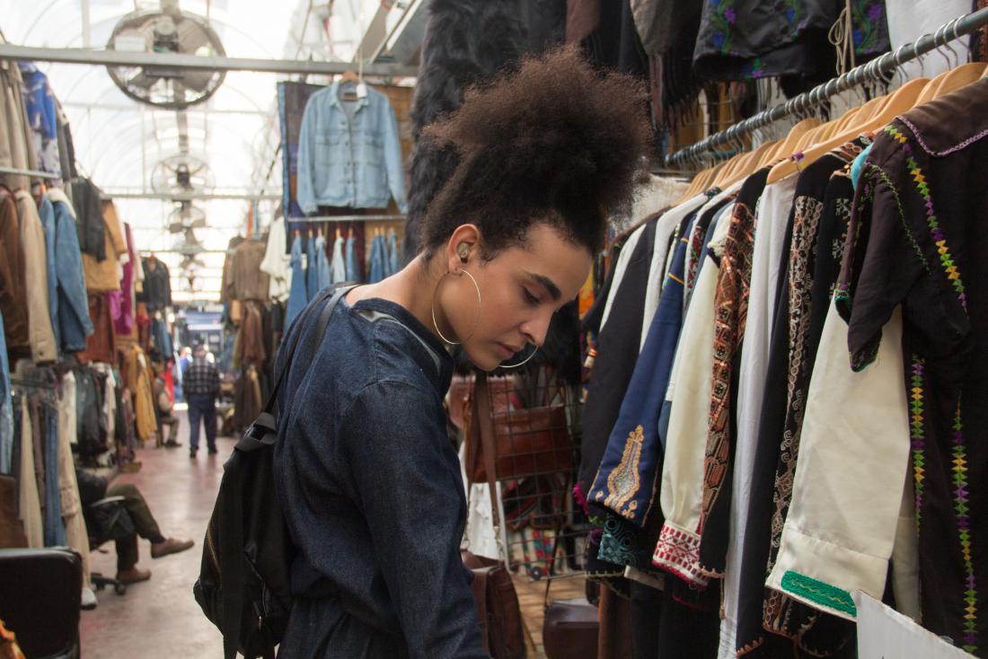 Woman with cluster a personality disorders outdoors shopping in flea market for clothes.
