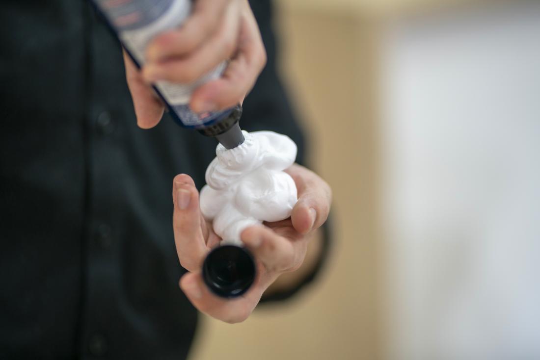 Person squirting hair styling mousse foam or cream into their hand