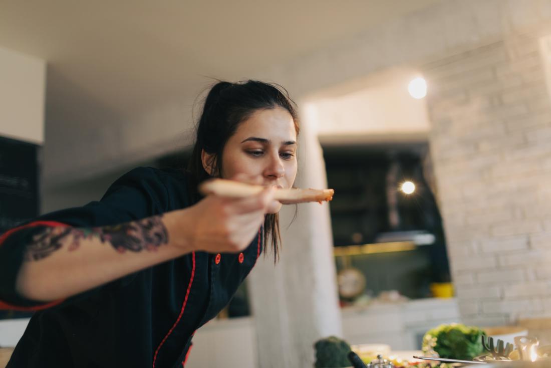 young woman tasting from wooden spoon with lost sense of taste
