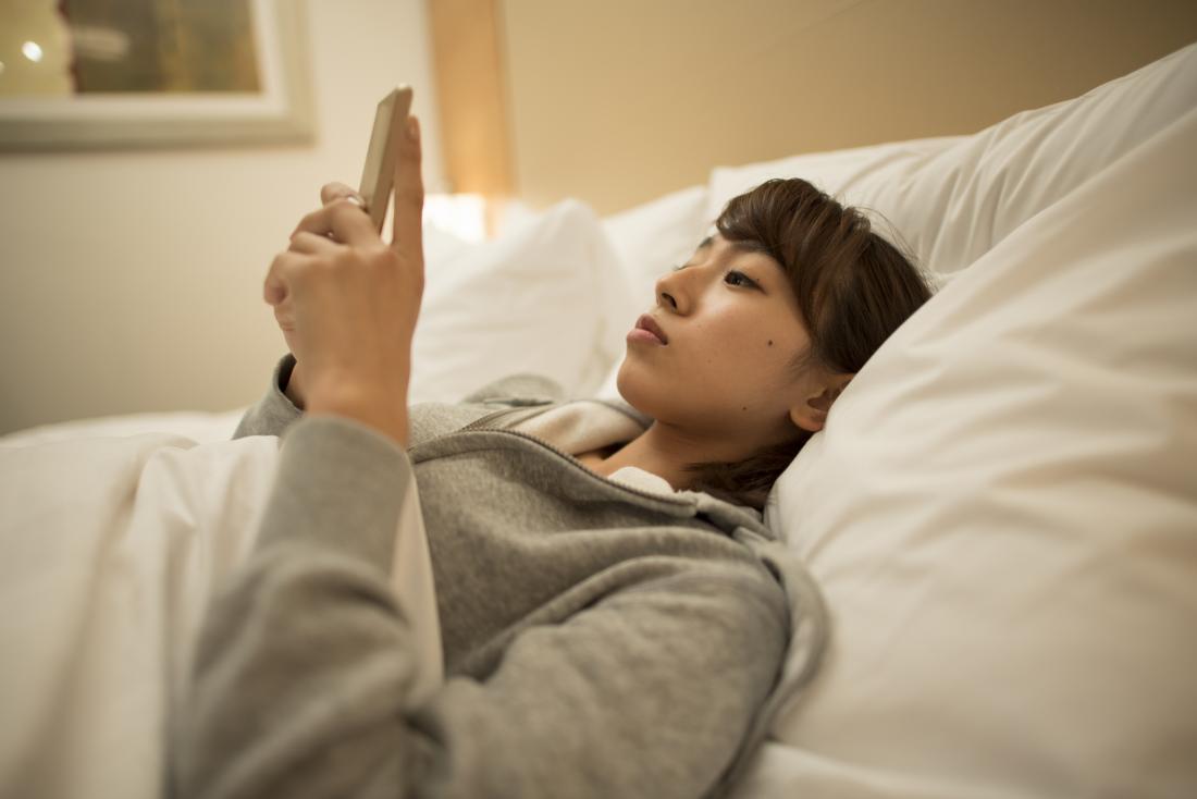 Mujer mirando el teléfono inteligente en la cama