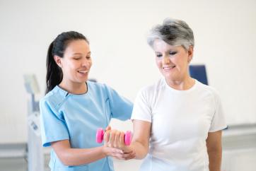 therapist helping woman to exercise arm