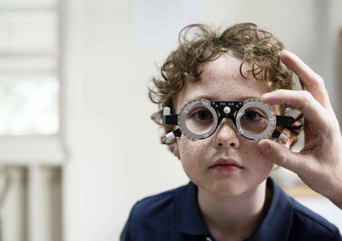 Child having eye exam check at opticians.