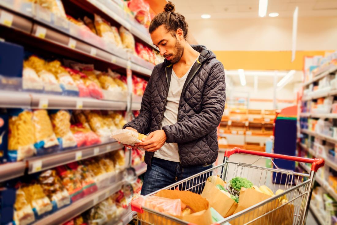 man in supermarket reading nutrition label