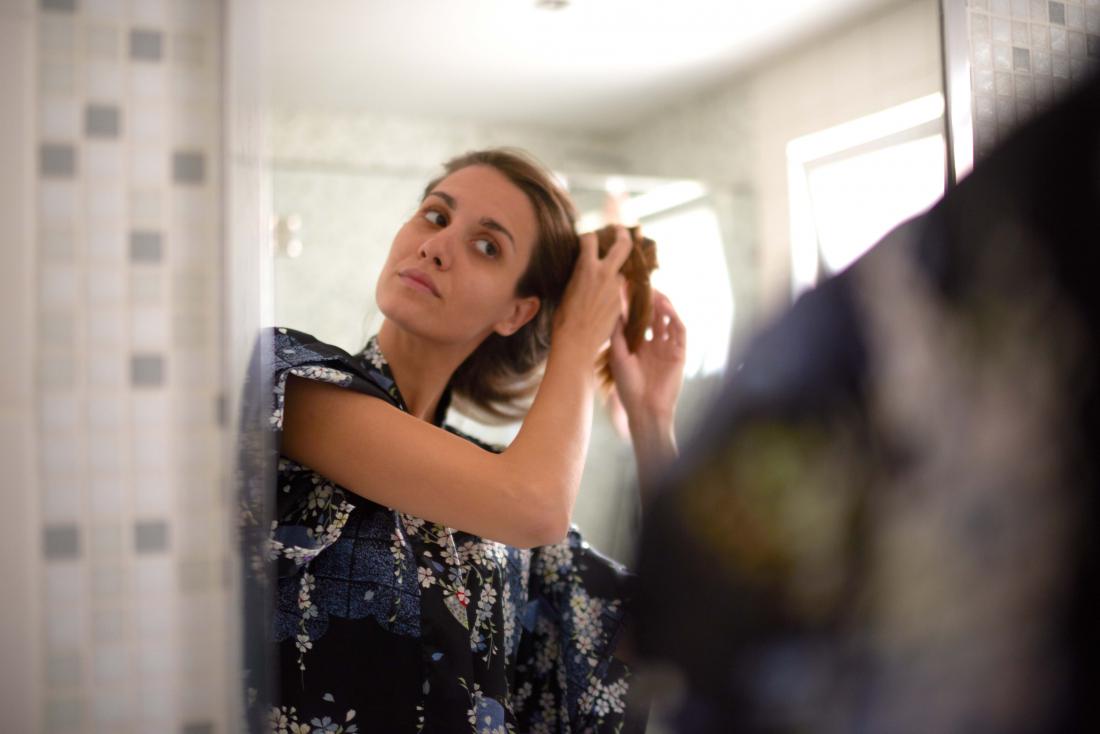 woman brushing hair in front of mirror
