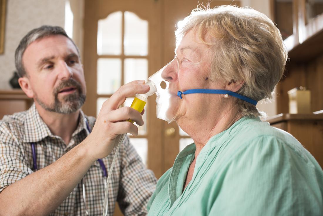 doctor helping senior female patient with oxygen mask