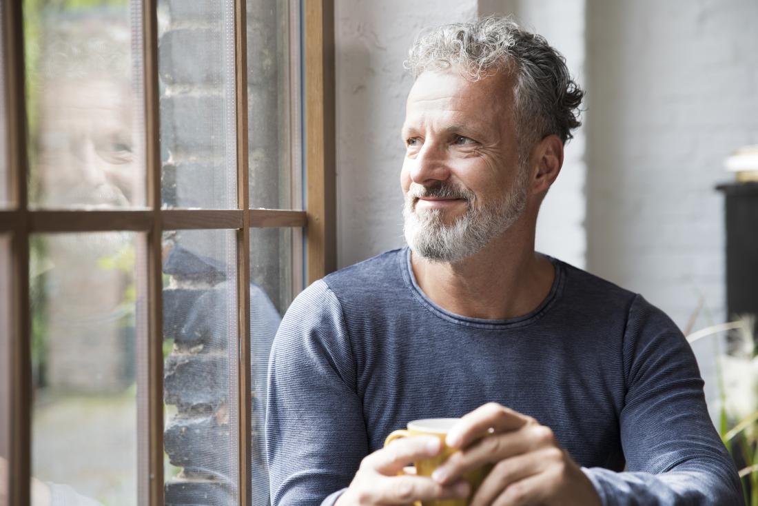 man relaxing with coffee by window